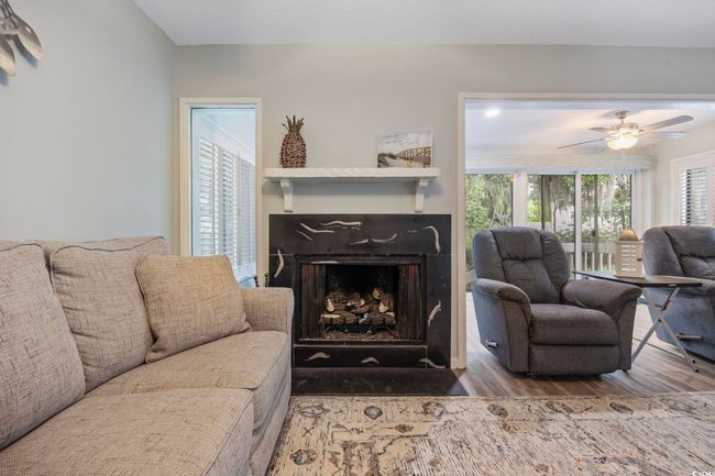 Living area featuring wood finished floors, a fireplace with flush hearth, and a ceiling fan | Image 17