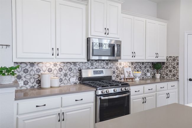 Kitchen with tasteful backsplash, white cabinets, and stainless steel appliances | Image 15