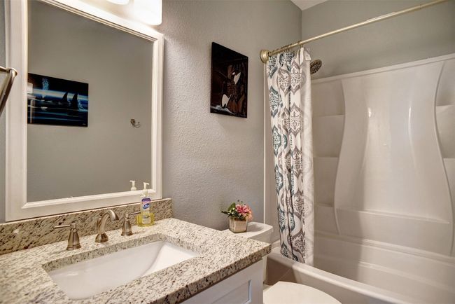 Bathroom with vanity, shower / bath combination with curtain, and a textured wall | Image 26