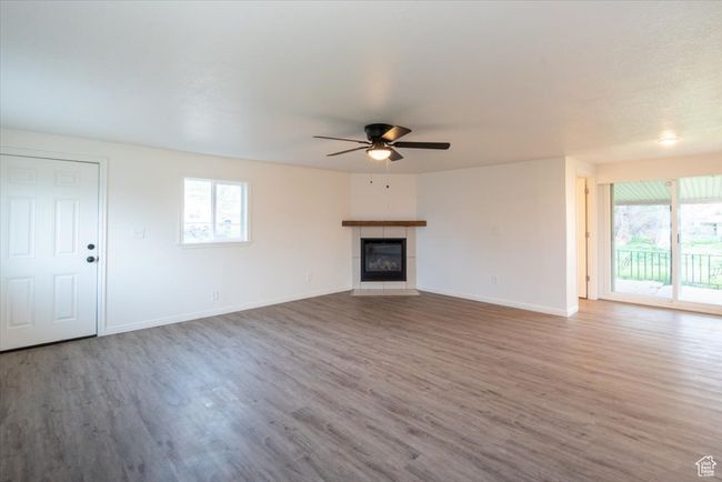 Unfurnished living room featuring a ceiling fan, plenty of natural light, and wood finished floors | Image 17
