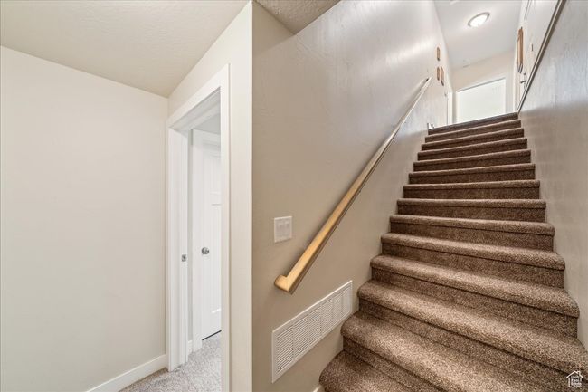 Stairs with baseboards, carpet flooring, and visible vents | Image 38
