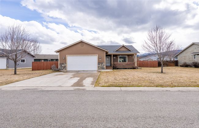 Ranch-style home with stone siding, concrete driveway, an attached garage, and fence | Image 33