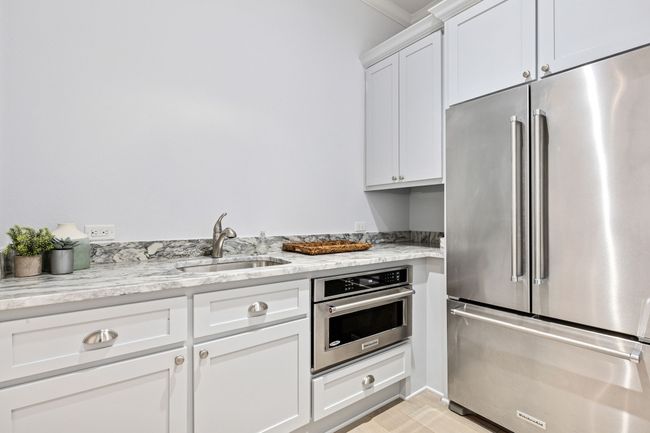Kitchen featuring white cabinetry, light stone counters, a sink, and stainless steel appliances | Image 19
