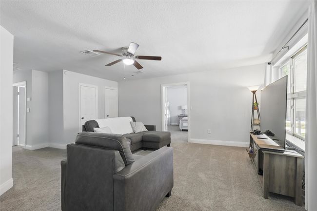 Living area featuring light carpet, a ceiling fan, baseboards, healthy amount of natural light, and a textured ceiling | Image 22