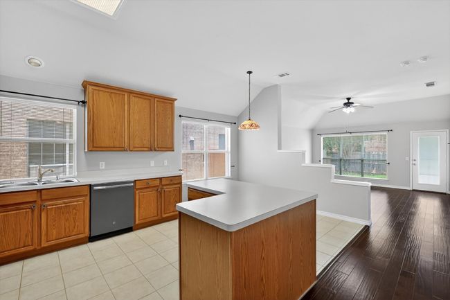 Kitchen with dishwasher, light countertops, vaulted ceiling, and brown cabinets | Image 6