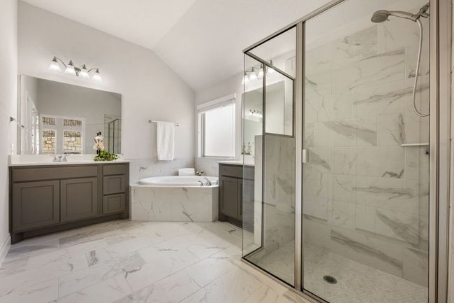 Full bathroom featuring lofted ceiling, two vanities, a stall shower, a bath, and marble finish floor | Image 20