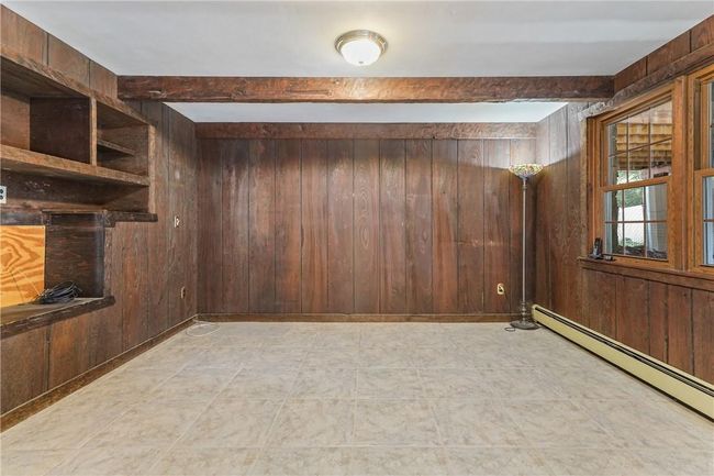 Lower Level exercise room featuring wood walls, light tile patterned floors, and baseboard heating | Image 22