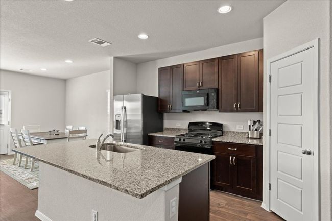Kitchen featuring black appliances, a sink, dark wood finished floors, dark brown cabinetry, and recessed lighting | Image 11