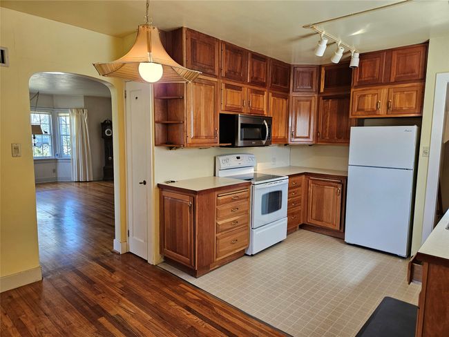 Kitchen with open shelves, light countertops, arched walkways, light wood-type flooring, and white appliances | Image 10