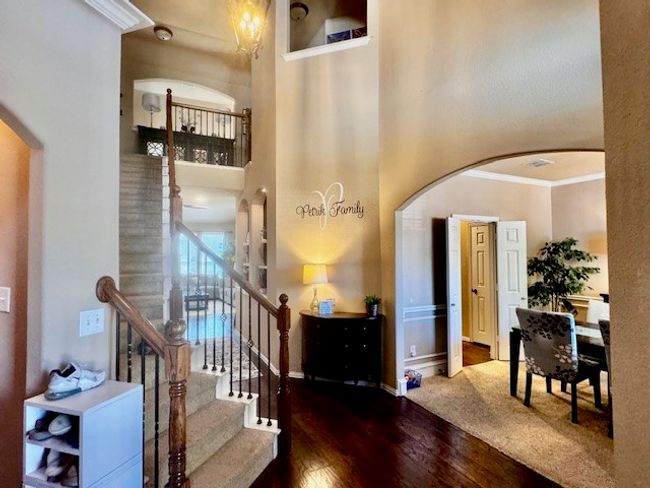 Entrance foyer with ornamental molding, a high ceiling, stairs, arched walkways, and wood-type flooring | Image 12