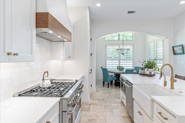Kitchen featuring custom range hood, appliances with stainless steel finishes, a sink, backsplash, and a chandelier | Image 9