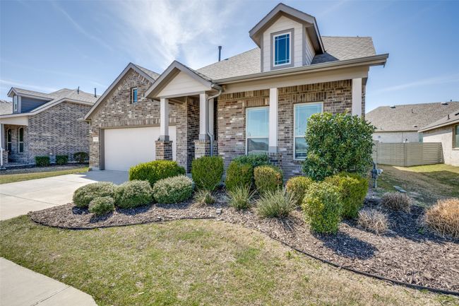 View of front facade with fence, concrete driveway, a front yard, an attached garage, and brick siding | Image 4