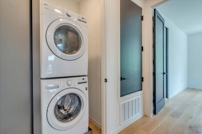 Laundry area featuring stacked washer / drying machine and light wood-style floors | Image 22