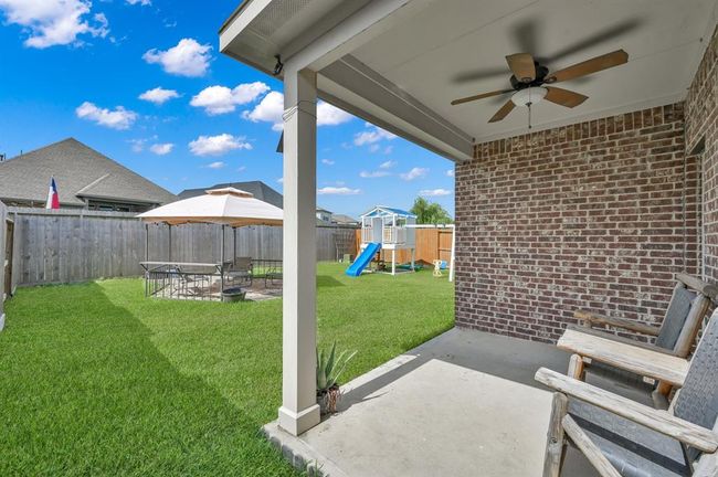 Spacious backyard featuring a lush green lawn, a playset with a slide for children, and a cozy patio area with a canopy for outdoor dining and relaxation. Ideal for family gatherings and playtime. | Image 29