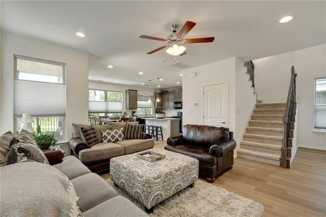 Living area featuring light wood finished floors, stairs, a ceiling fan, and recessed lighting | Image 6