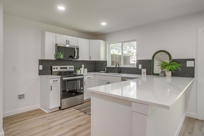Kitchen with appliances with stainless steel finishes, a peninsula, light wood-type flooring, light countertops, and recessed lighting | Image 10