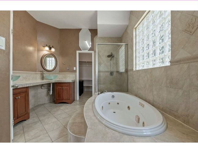 Full bathroom featuring a stall shower, a tub with jets, vanity, tile walls, and a spacious closet | Image 13