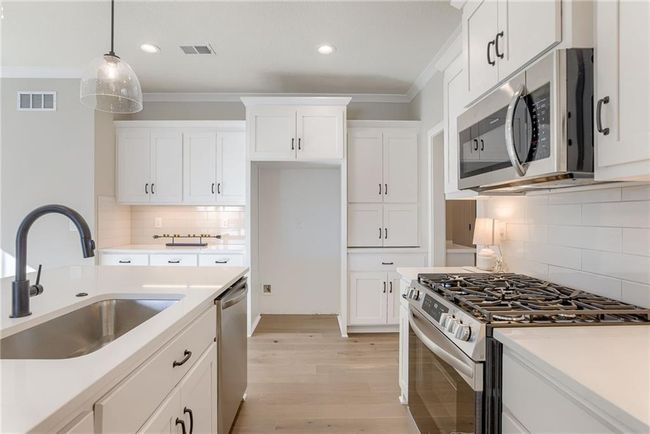 Kitchen featuring stainless steel appliances, visible vents, a sink, and pendant lighting | Image 11
