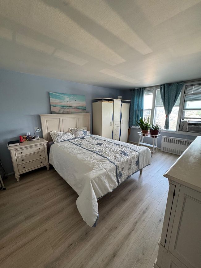 Bedroom with wood finished floors, cooling unit, and radiator | Image 4