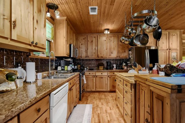 Kitchen featuring wood ceiling, a sink, appliances with stainless steel finishes, visible vents, and decorative backsplash | Image 19