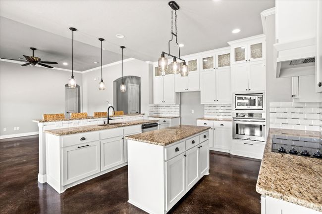 Kitchen featuring appliances with stainless steel finishes, concrete floors, a sink, a center island, and tasteful backsplash | Image 13