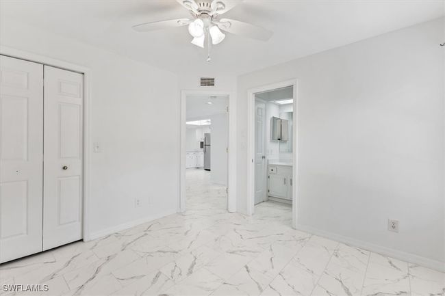 Unfurnished bedroom featuring a closet, ensuite bath, stainless steel refrigerator, light tile patterned flooring, and ceiling fan | Image 34