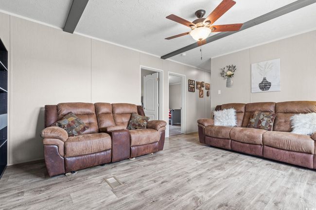 Living area featuring wood finished floors, a ceiling fan, crown molding, and a textured ceiling | Image 23