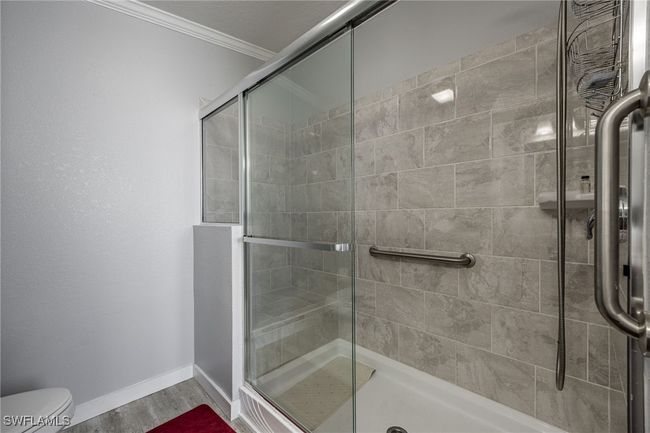 Full bath with a shower stall, baseboards, toilet, ornamental molding, and wood finished floors | Image 27