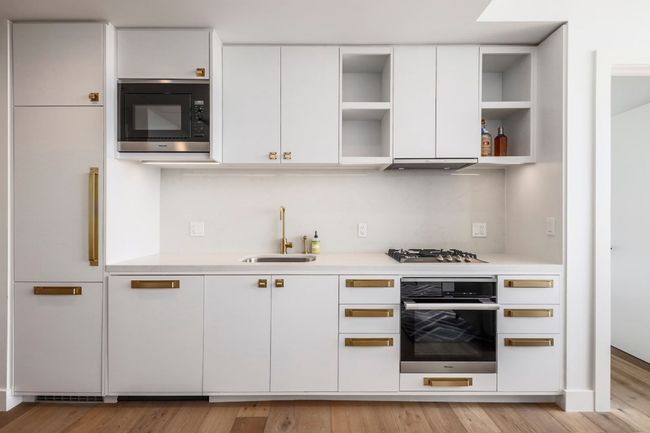 Kitchen featuring open shelves, a sink, built in appliances, light countertops, and white cabinetry | Image 8