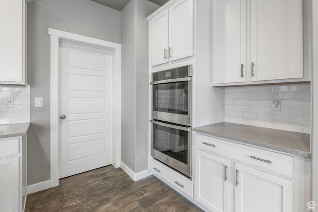 Kitchen with backsplash, baseboards, dark wood finished floors, and double oven | Image 17