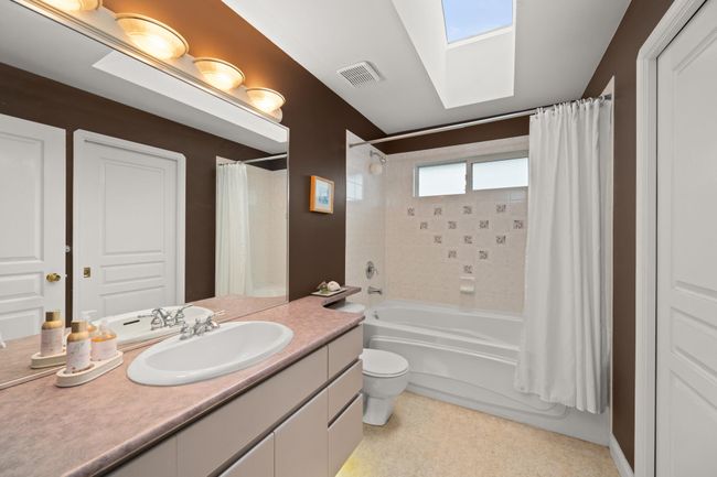 Bathroom with visible vents, shower / bath combination with curtain, vanity, and toilet | Image 31