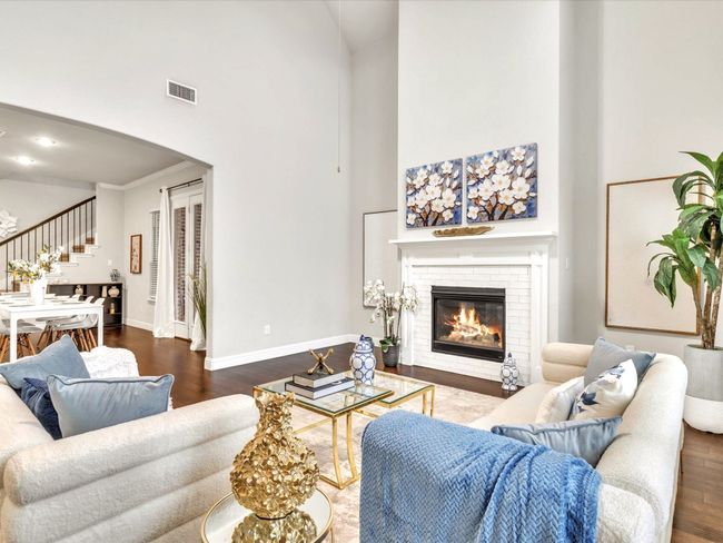 Living area featuring a towering ceiling, stairs, wood finished floors, arched walkways, and a brick fireplace | Image 6