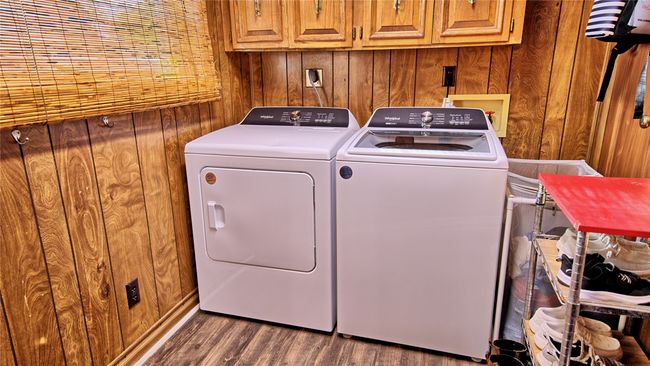 Washroom featuring cabinet space, wood walls, washer and dryer, and dark wood-style flooring | Image 10