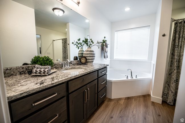 Bathroom with wood finished floors, vanity, a garden tub, a shower with curtain, and recessed lighting | Image 6