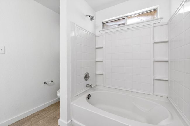 Bathroom with toilet, wood finished floors, tub / shower combination, and baseboards | Image 31