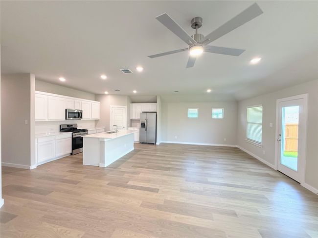 Kitchen with open floor plan, stainless steel appliances, light wood-type flooring, recessed lighting, and white cabinetry | Image 12