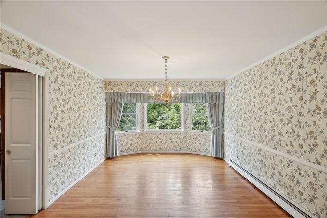 Unfurnished dining area featuring a baseboard radiator, a chandelier, hardwood / wood-style floors, and wallpapered walls | Image 17