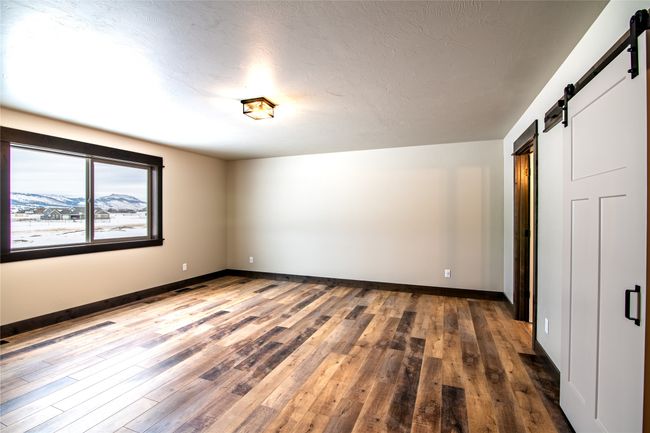 Unfurnished bedroom with dark wood-type flooring, a barn door, and a textured ceiling | Image 12