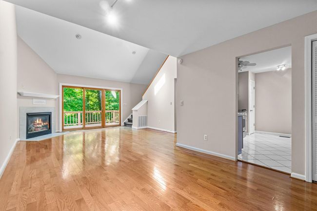 Unfurnished living room Dining Area featuring lofted ceiling, light wood finished floors, stairway, a tile fireplace, and baseboards | Image 7