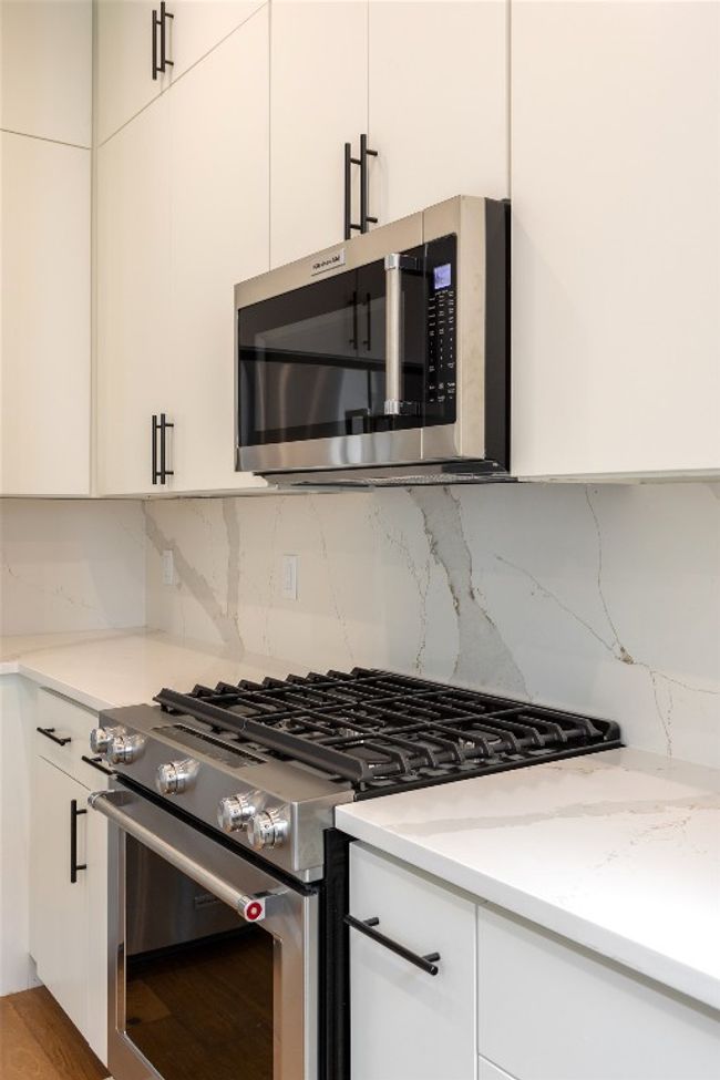 Kitchen featuring appliances with stainless steel finishes, decorative backsplash, white cabinetry, and modern cabinets | Image 15