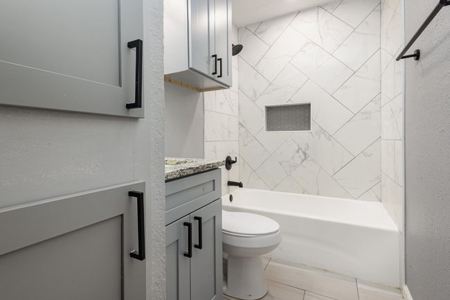 Full bath with vanity, toilet, shower combination, and a textured wall | Image 37