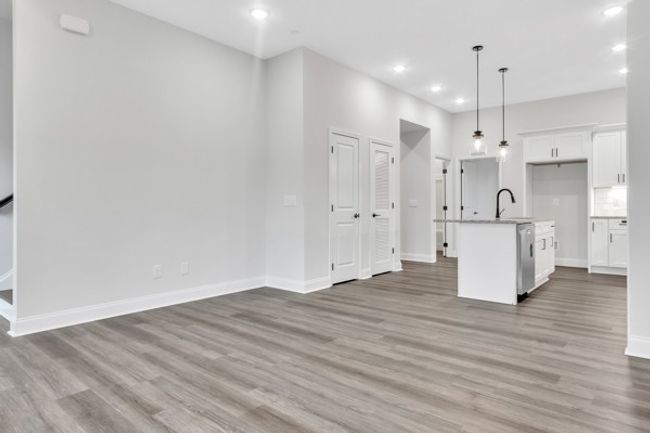 A look back from the front part of the living space toward the kitchen with the guest bedroom behind and to the left entry to stairs up to the second and third bedroom and laundry room. | Image 18