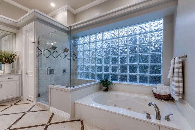 Another view of the primary bathroom, with a double-headed shower, jetted tub, and a large glass-block window for natural light and privacy. | Image 19