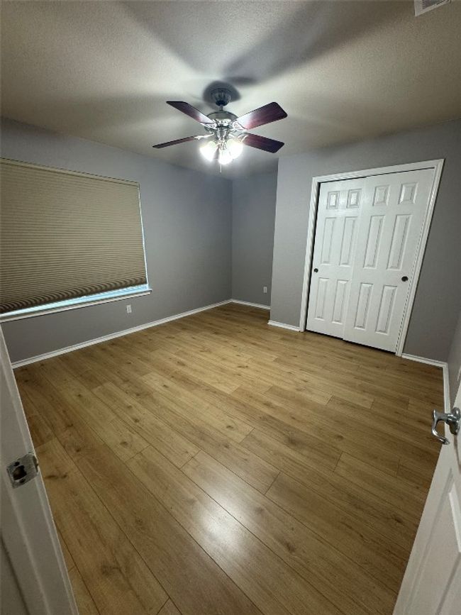 Unfurnished bedroom with wood finished floors, baseboards, a ceiling fan, a closet, and a textured ceiling | Image 21