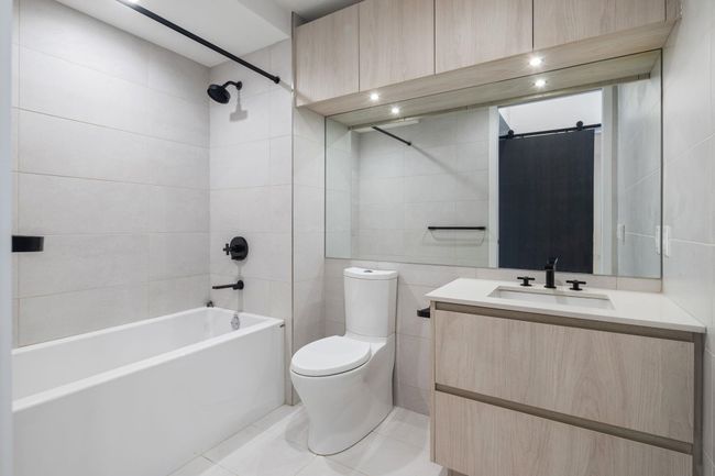Bathroom with vanity, shower / bath combination, tile walls, toilet, and tile patterned floors | Image 19