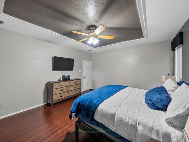 Bedroom featuring visible vents, baseboards, wood finished floors, and ceiling fan | Image 21
