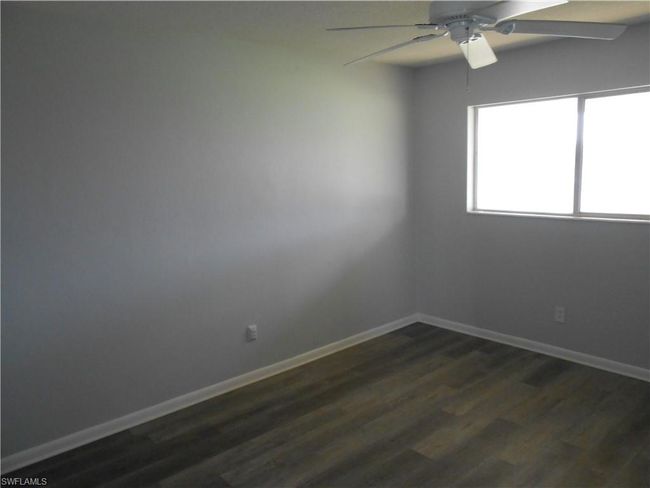 Empty room with dark wood-type flooring, baseboards, and a ceiling fan | Image 12
