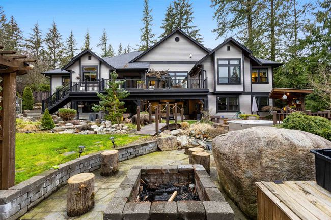 Rear view of property featuring a lawn, a patio area, a fire pit, a wooden deck, and stairs | Image 35