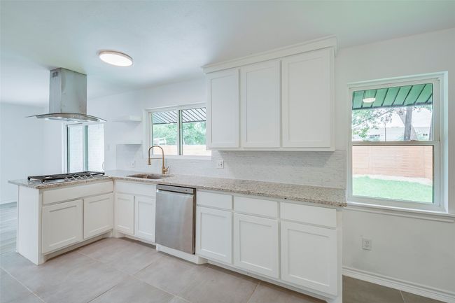 Kitchen with appliances with stainless steel finishes, island exhaust hood, tasteful backsplash, and white cabinetry | Image 15