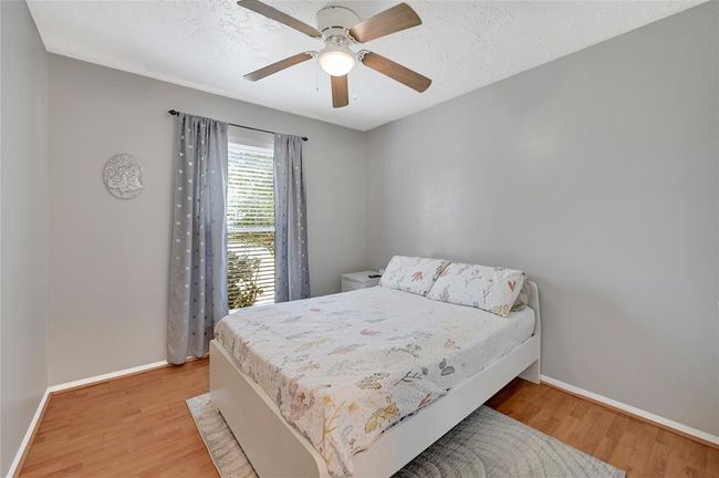 Cozy second bedroom with natural light, stylish ceiling fan, and elegant flooring. Perfect for guests room. | Image 14